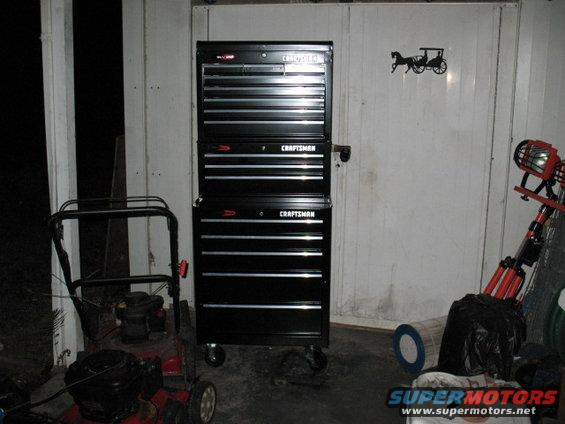 Black Craftsman tool chest stacked on a red lawn mower in a garage
