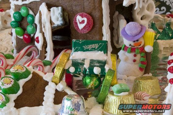 Gingerbread house with candy decorations, including a snowman and Andes mints