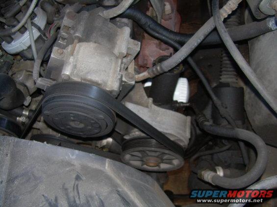 Close-up of a power steering pump with a serpentine belt on pulleys in an engine bay