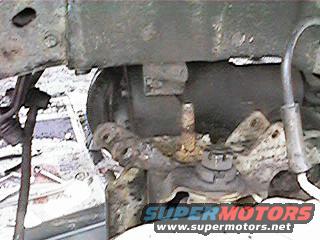 Close-up of rusty front suspension component with SUPERMOTORS.NET watermark