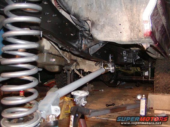 Undercarriage view of vehicle suspension with large coil spring and gray control arm