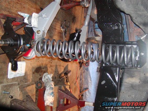 close-up of vehicle suspension parts, including springs and steering knuckle, in a workshop