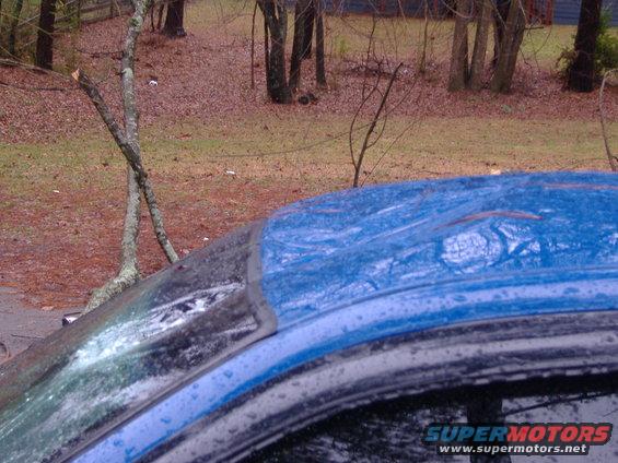 Blue car roof showing damage and water droplets