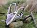 1986 Ford Bronco - Vehicle doors are seen discarded in a grassy, wooded area with logs and branches.