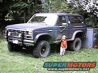 Dark blue 1980s Ford Bronco with a child standing next to it