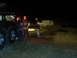 1978 Ford Bronco - A group of people are gathered around a white SUV that appears to be stuck in the dirt at night, with a large truck also present.