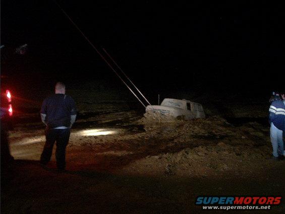 1978 Ford Bronco stuck in mud at night, being pulled by tow ropes