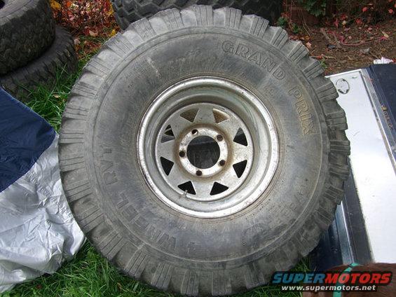 Off-road tire with 'GRAND PRIX' and 'WHEEL' text on the sidewall, mounted on a silver rim