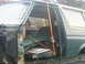 1990 Ford Bronco - This green Ford Bronco, likely from the late 1980s, is being transported on a trailer with its door ajar and secured by straps.
