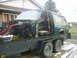 1990 Ford Bronco - The body of a green 1990 Ford Bronco is secured to a flatbed trailer, with its front end disassembled.