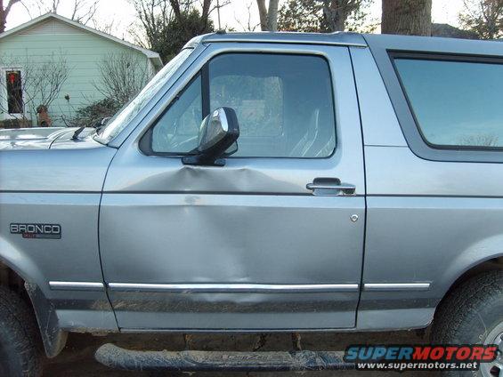 1995 Ford Bronco side view showing a large dent on the driver's door