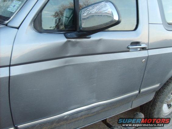 Silver SUV door with significant denting near the handle and along the body line