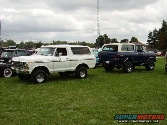 1978 Ford Bronco in white and a second 1978 Ford Bronco in blue parked on grass