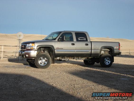 2006 GMC Sierra 2500 pickup truck, lifted, parked on gravel with a windmill in the background