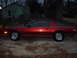 1995 Ford Bronco - A side view of a red coupe parked on a concrete driveway at dusk.