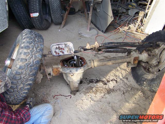 Front axle assembly with differential cover removed, tire, and steering components