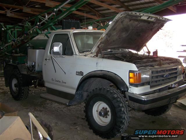 White Ford F-Series truck with hood open, fitted with a large green sprayer apparatus on the rear bed