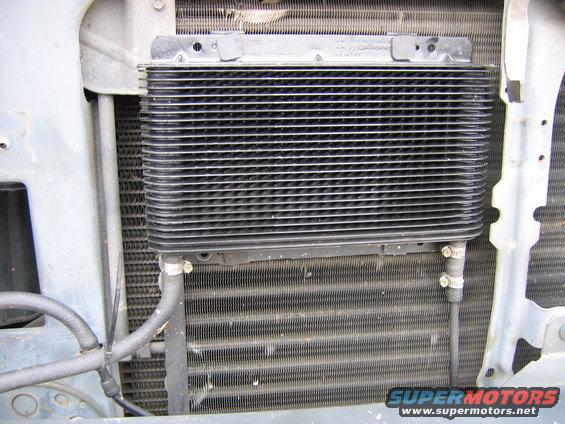 Transmission cooler mounted in front of a vehicle's radiator, with hoses attached