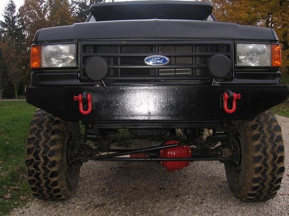 1991 Ford Bronco front view, showing grille with Ford logo, aftermarket bumper with red tow hooks, and large off-road tires