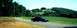 1997 Ford Crown Victoria - A black 1997 Ford Crown Victoria sedan travels down a winding country road under a clear blue sky.