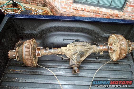 Rear axle assembly with drum brakes, rusty, in a pickup truck bed