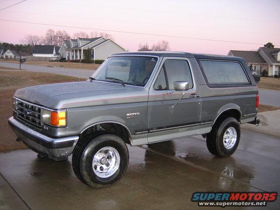 Gray Ford Bronco parked on wet driveway, houses in background