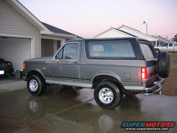 Gray Ford Bronco parked in a driveway, 3/4 front view, showing its side profile and rear tire carrier