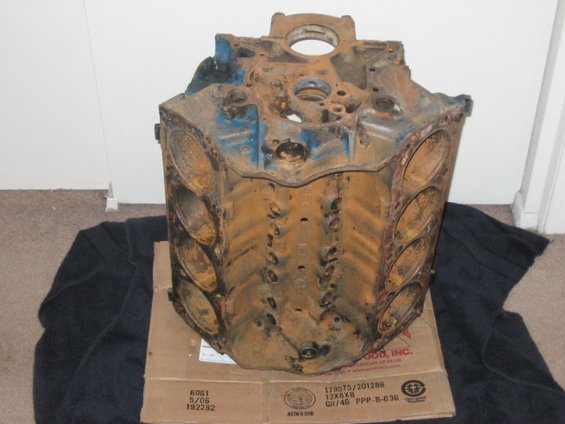 Rusted engine block with blue paint remnants, resting on a cardboard box