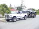 2001 Dodge 2500 - White Dodge 2500 pickup truck is seen towing a custom monster truck on a trailer.
