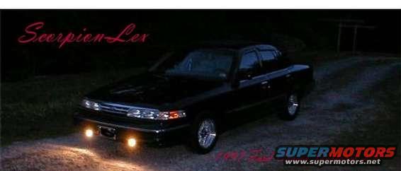 Black sedan with aftermarket wheels and fog lights parked at night