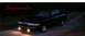 1997 Ford Crown Victoria - A black sedan is parked on a dirt road at night, illuminated by its headlights and fog lights.