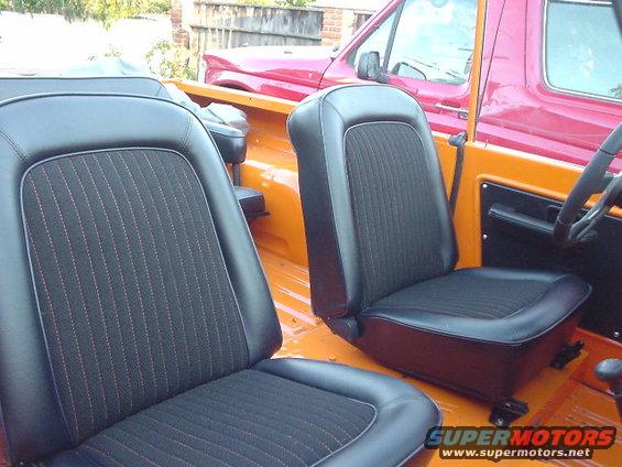1977 Ford Bronco interior with black seats and orange floor. Another red vehicle is visible behind