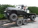 2001 Dodge 2500 - A heavily modified black flatbed truck with large off-road tires is positioned on a trailer.