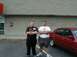 1997 Ford Crown Victoria - A red 1997 Ford Crown Victoria is parked next to two men in front of a brick building.