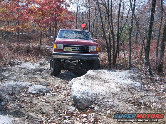 1990 Ford Bronco navigating a rocky trail with lifted suspension