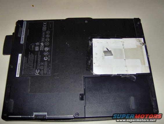 underside of a laptop computer with labels and tape