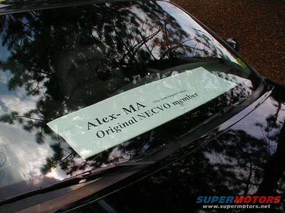 Black car windshield with a sign reading "Alex- MA Original NECVO member"