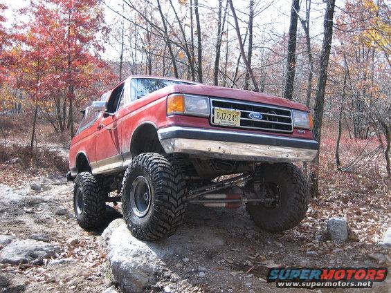 Lifted red Ford Bronco on rocks, yellow license plate RJZ-245