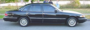 Side view of a black 1997 Ford Crown Victoria with chrome trim and aftermarket wheels