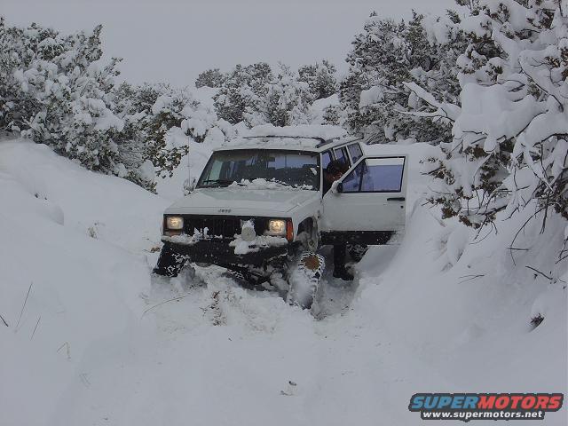 White Jeep Cherokee XJ stuck in deep snow, driver's door open
