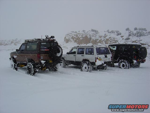 Brown Ford Bronco II with roof rack and spare tire in snow