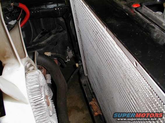 Radiator and fan shroud in engine bay. Supermotors.net logo visible