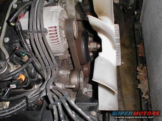 Close-up of engine parts including alternator, belts, pulleys, and fan