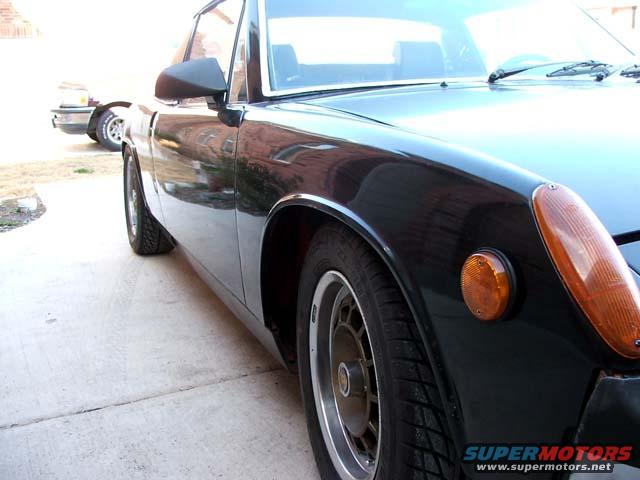 Side view of a black sports car, another car is parked behind it
