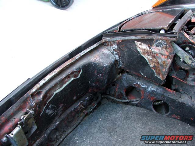 Close-up of a heavily rusted car chassis, showing structural damage and wear