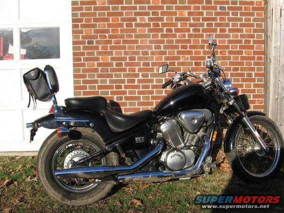 Black motorcycle with saddlebags parked next to a brick wall and garage door
