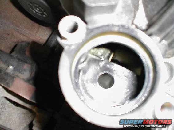 Close-up of a metal engine component with a circular opening. Some internal parts are visible within the opening