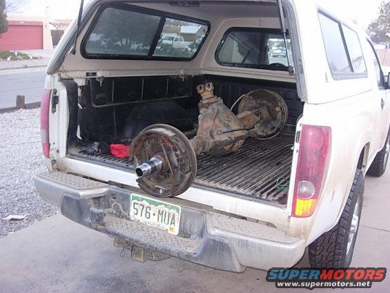 White pickup truck rear view with differential and brake assemblies in bed