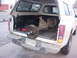 1987 Ford Bronco - A white pickup truck carries a differential and brake assemblies in its bed, with a license plate visible.