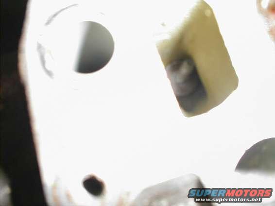 close up of a light-colored engine part with a dark interior section, and a dark cylindrical opening